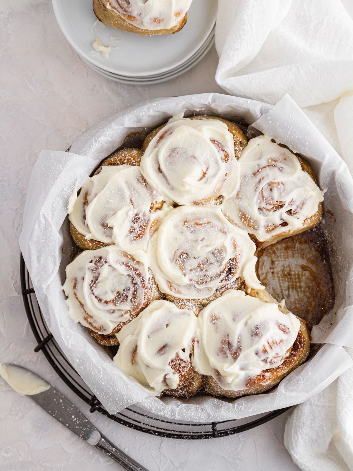 sourdough cinnamon rolls in a pan with one taken out on a plate.