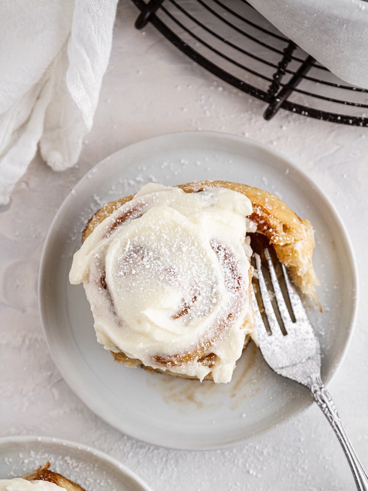 sourdough cinnamon roll on a plate with a forkful taken out.