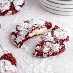 red velvet cookies on a surface covered with powdered sugar.