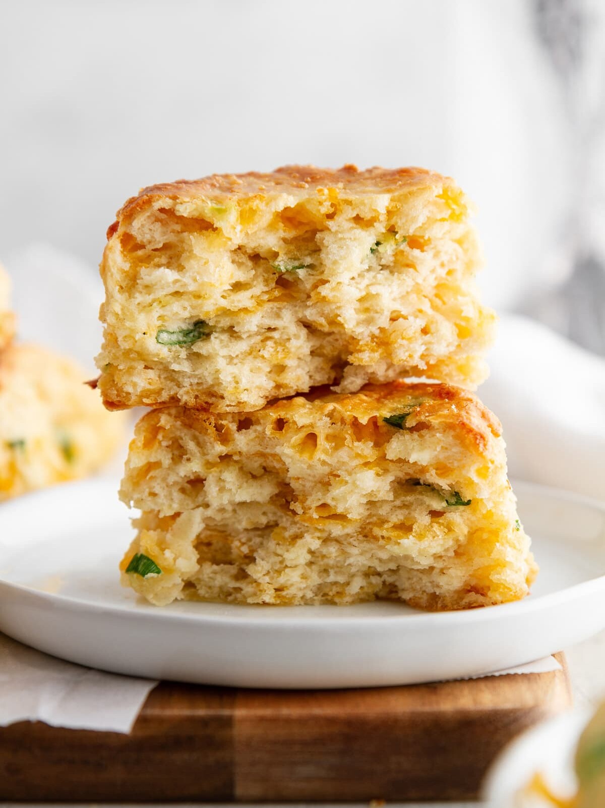cheddar-scallion biscuit broken in half and stacked on a plate.