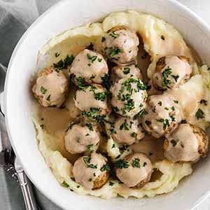 crockpot Swedish meatballs in a bowl with mashed potatoes.
