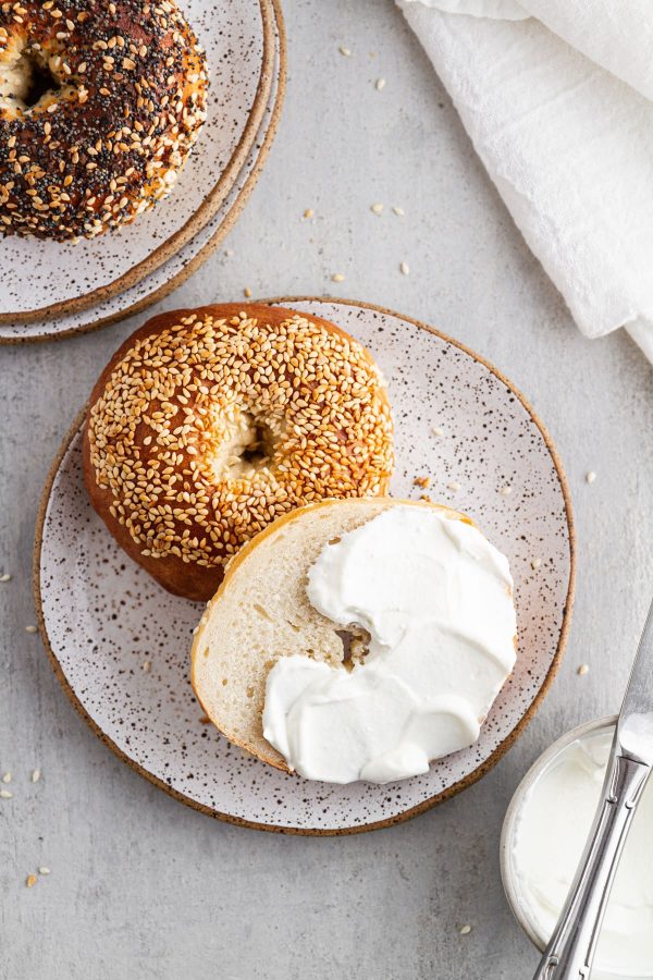 Montreal bagel on a plate cut in half with cream cheese on top