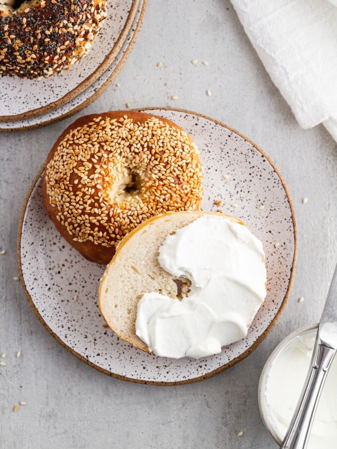 sesame topped montreal bagel sliced in half and spread with cream cheese.