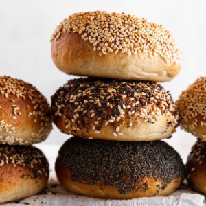 stack of 3 bagels with different toppings and white background.