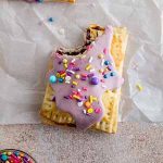 pop tart on a surface with a bite taken out of it.
