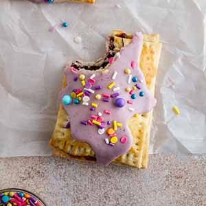 pop tart on a surface with a bite taken out of it.