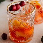 glass of cranberry old fashioned on a surface.