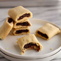 stack of homemade fig newtons on a plate with a bite taken out of one