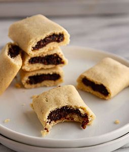 stack of homemade fig newtons on a plate with a bite taken out of one