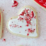 heart shaped cookie iced with strawberries on top.