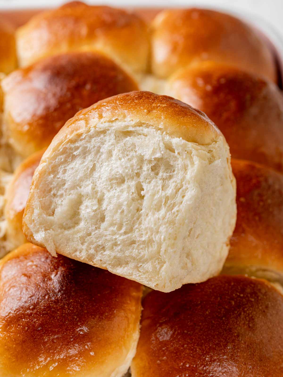 close up of single roll on top of all baked rolls in dish.
