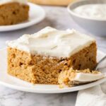 slice of banana bars with cream cheese frosting on white plate.