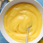 Lemon curd in a bowl with a silver spoon.