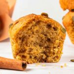 A pumpkin muffin next to a cinnamon stick.