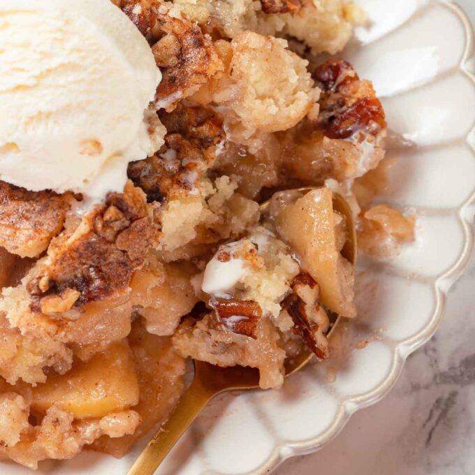 A scoop of ice cream served on top of a slice of apple dump cake.