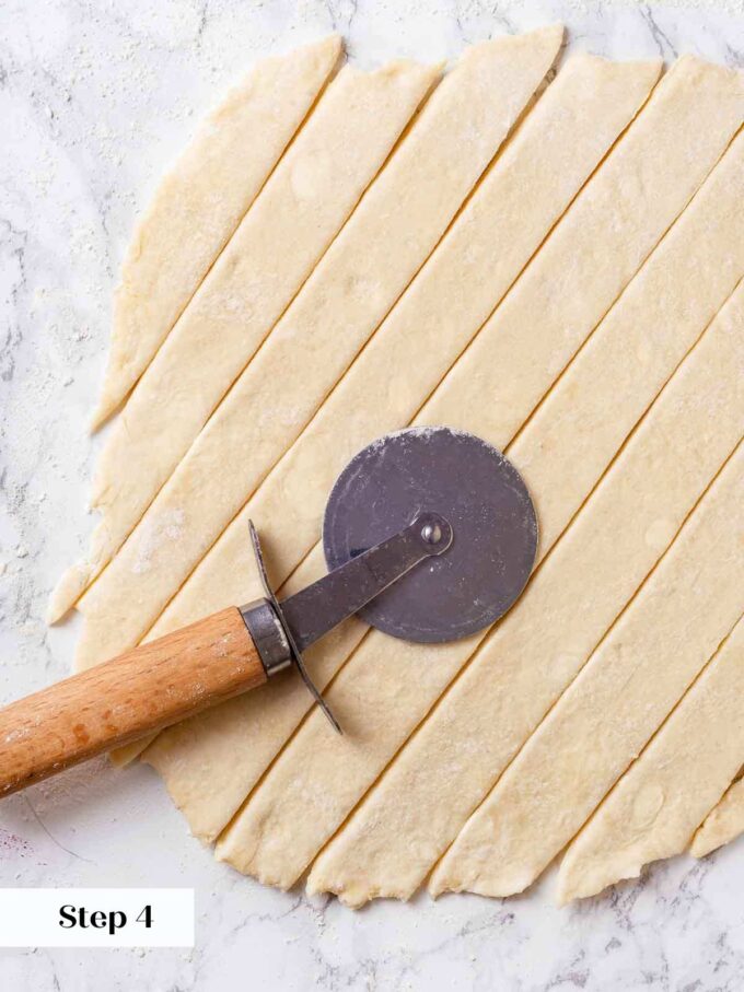 slicing rolled pie dough for lattice crust with pizza cutter.