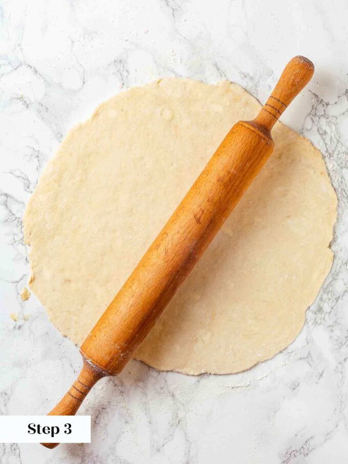 rolling pie dough thin with wooden vintage rolling pin.