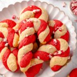 Candy cane cookies elegantly arranged on a white scalloped plate.