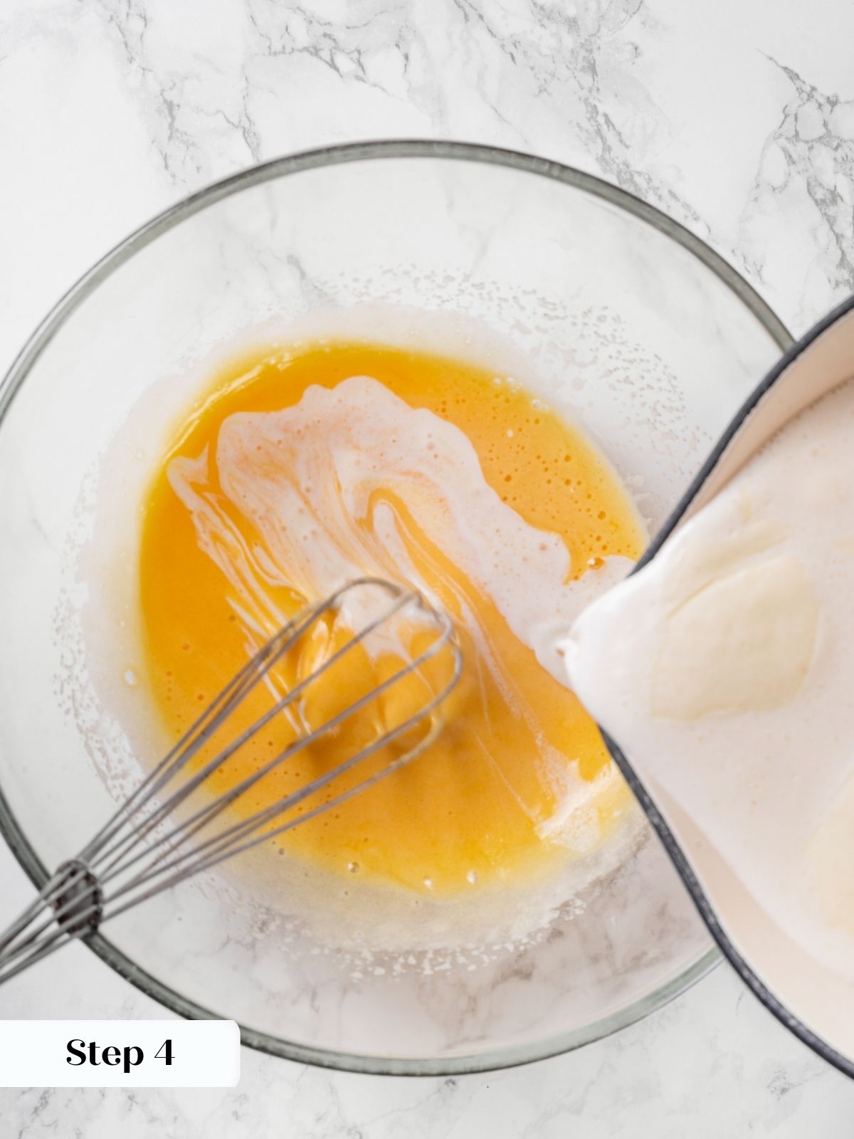 Warm cream being poured into whisked eggs to create the creme brulee custard.