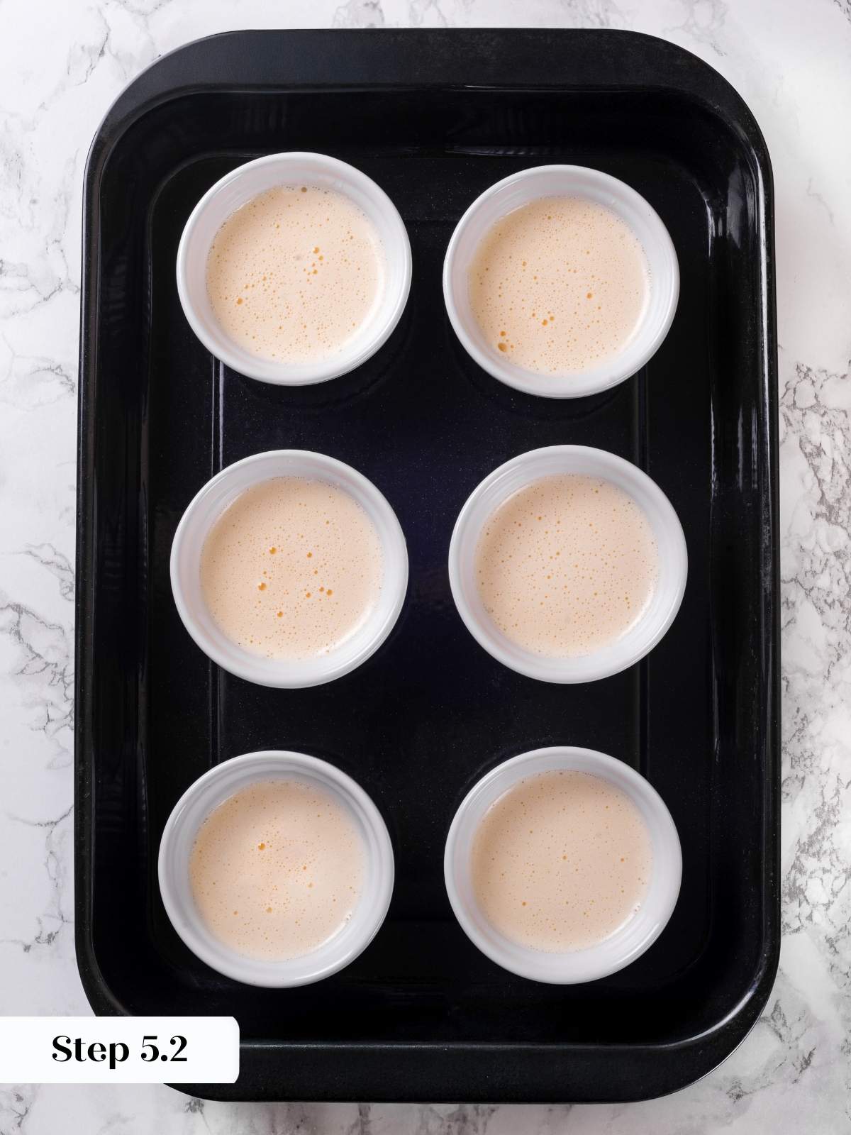 Unbaked creme brulee custards set in ramekins, waiting to go into the oven.