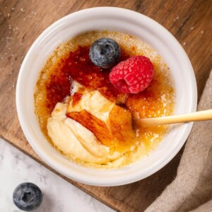 A creme brulee with a spoonful scooped out, revealing its velvety custard beneath the caramelized top.