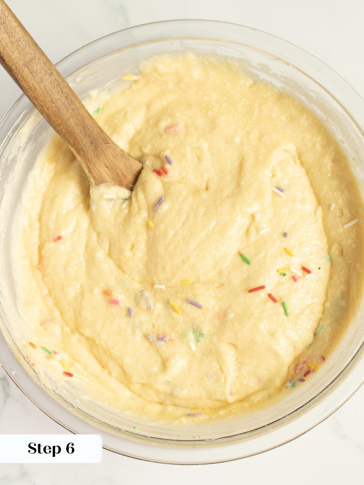 Folding rainbow sprinkles gently into vanilla cake batter.