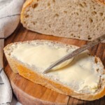 A warm slice of peasant bread spread with butter, ready to eat.