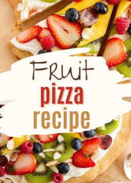 A round fruit pizza with sliced strawberries, kiwi, and blueberries on a cookie crust.