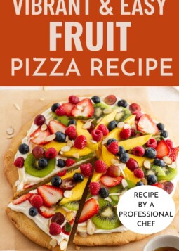 Fruit pizza topped with cream cheese frosting and colorful fruit arranged.