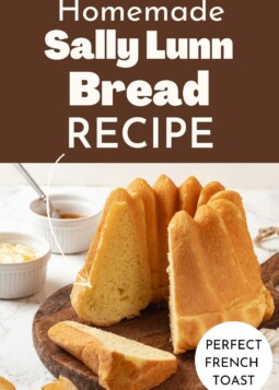 A golden loaf of Sally Lunn bread cooling on a wood board.