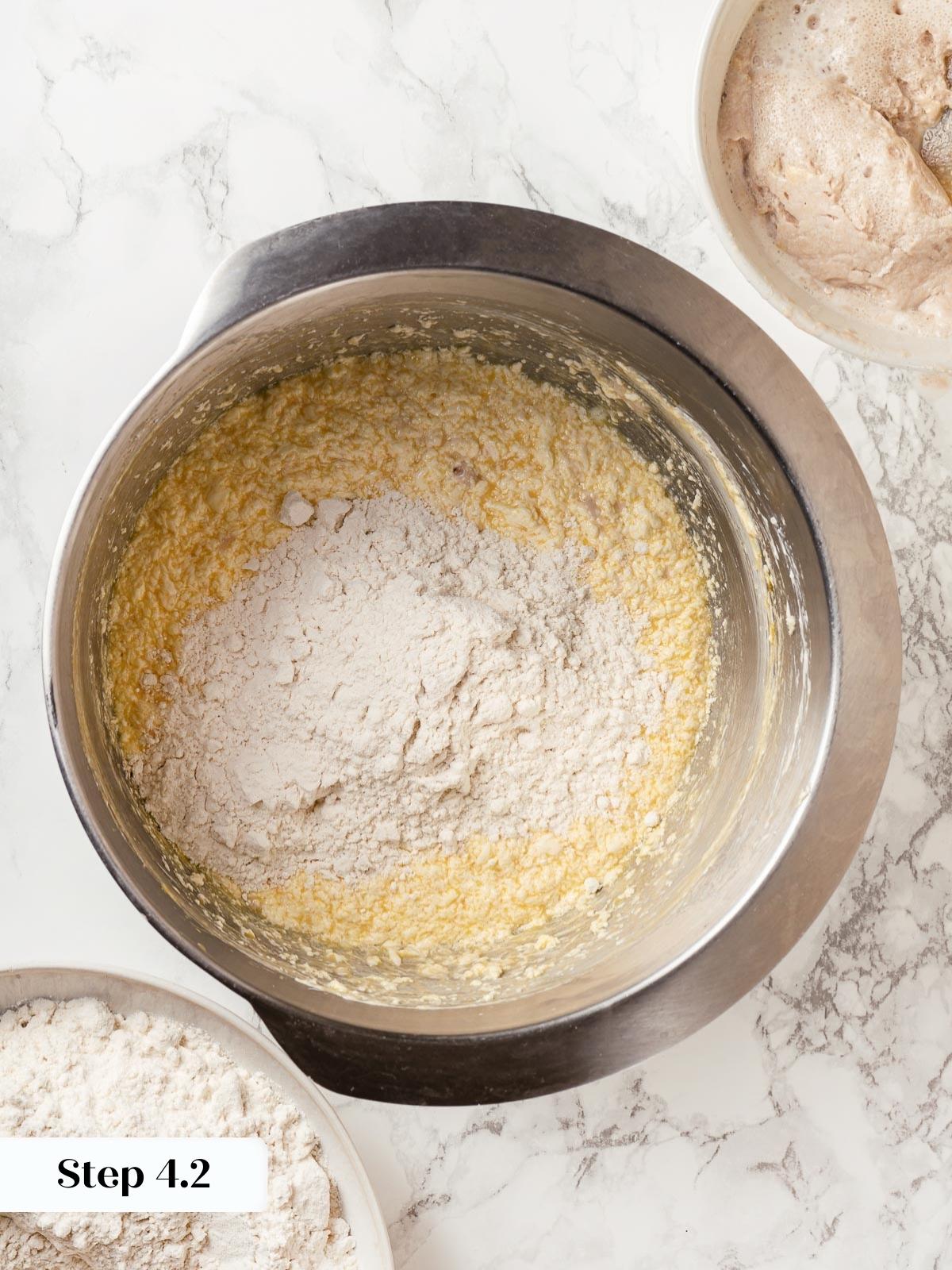 Flour being added gradually to wet ingredients in a bowl.