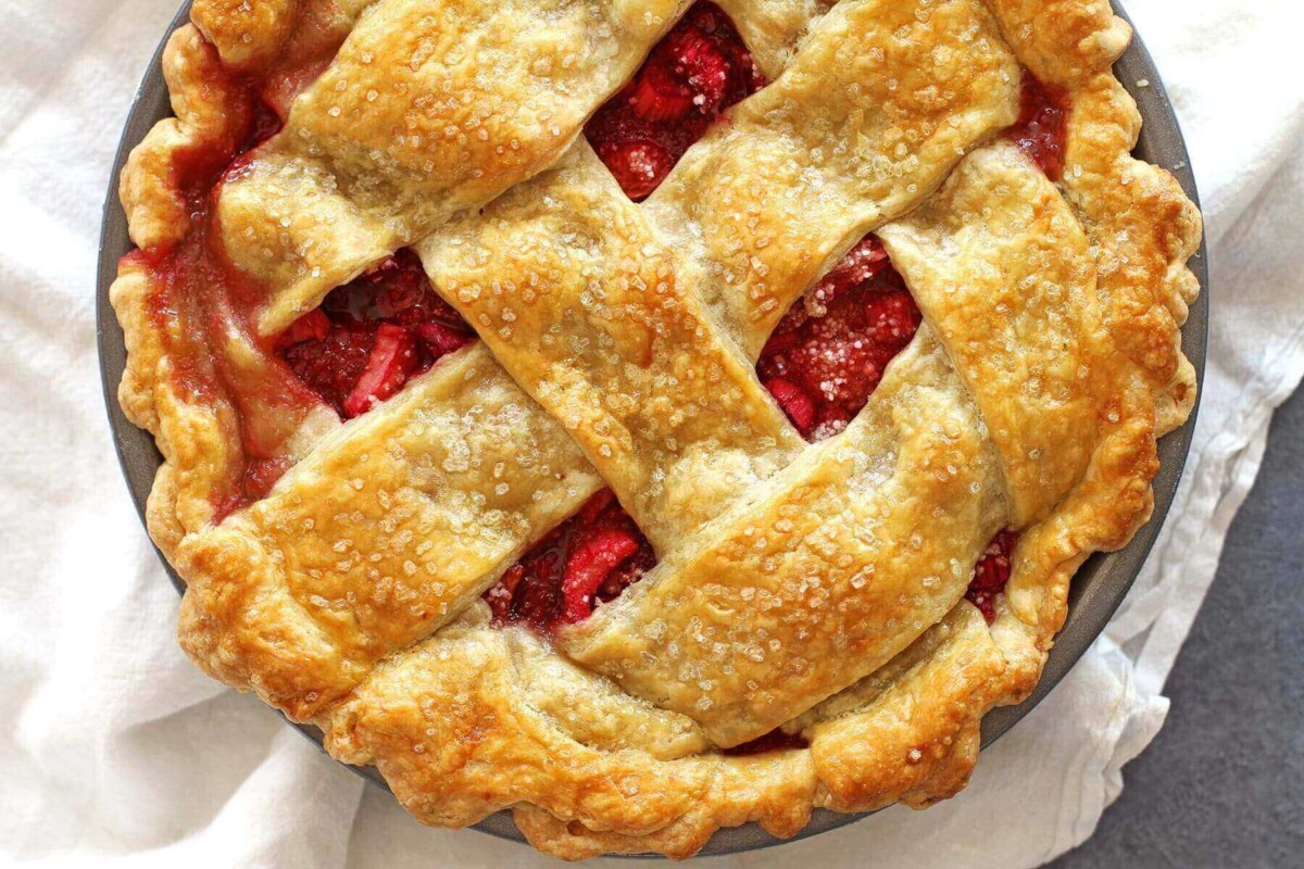 Strawberry rhubarb pie with a woven lattice top and juicy filling peeking through.