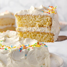 Vanilla cake slice being lifted with a cake server.