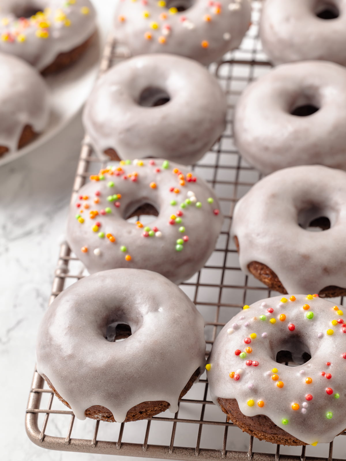 Chocolate donuts arranged on a wire rack to cool after adding the glaze.