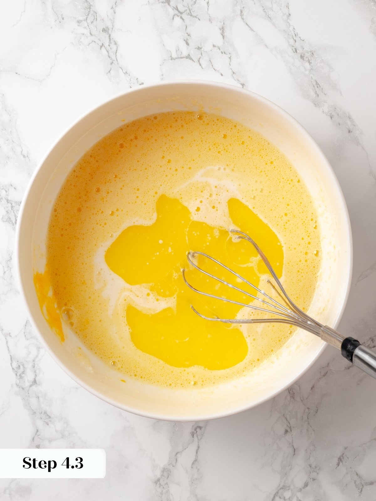 Melted butter and milk being added to a mixing bowl with the egg and sugar mixture.