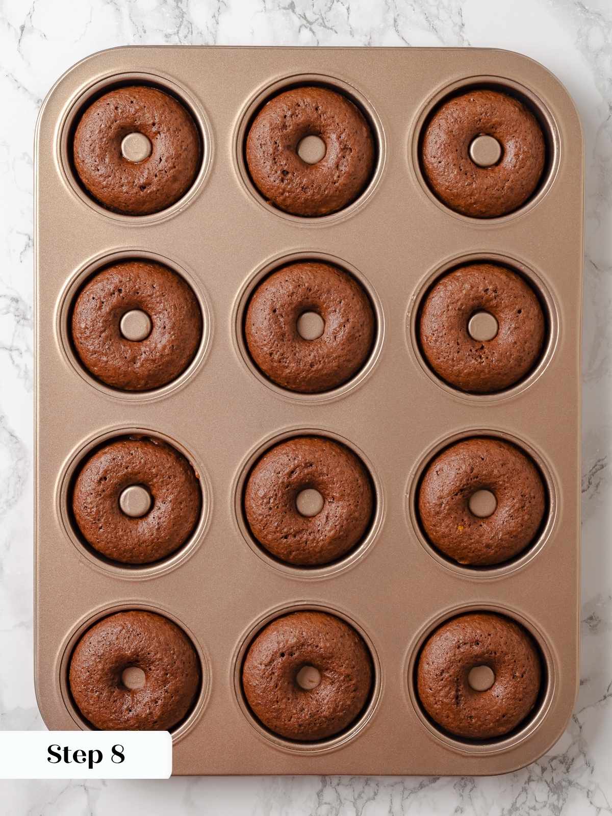 Baked chocolate donuts fresh from the oven, still sitting in the donut baking pan.