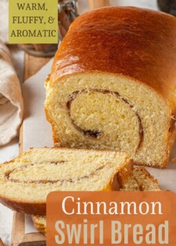 Cinnamon swirl loaf cut open on a cutting board with tight crumb and toasted edges showing.