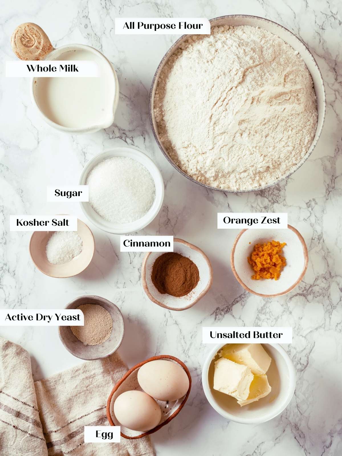 Measured ingredients for cinnamon bread including flour, butter, milk, and yeast arranged neatly.