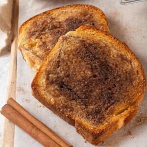 Cinnamon toast slices on parchment paper with caramelized cinnamon sugar and golden brown edges.