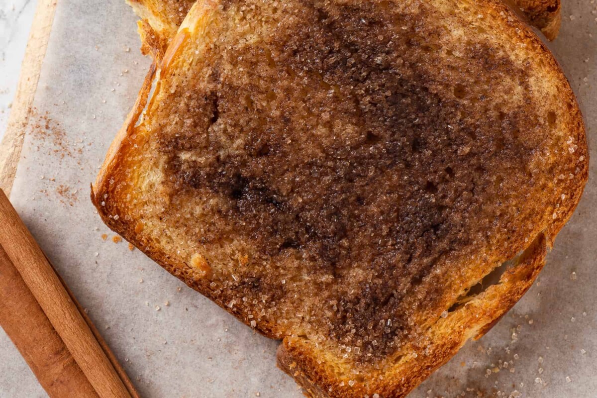 White sugar granules and cinnamon show on buttery toast.