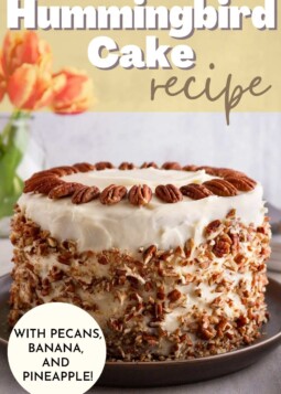 Cake with white frosting beautifully decorated with pecans on the top, and crushed pecans around the sides.