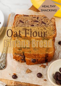 Banana bread slices stacked on a wooden board, crumbly edges and cinnamon flecks showing clearly.