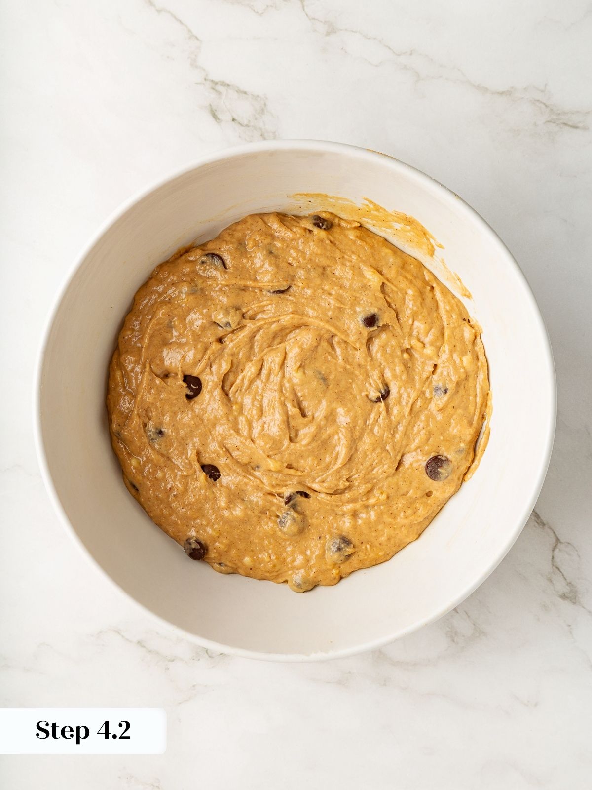 Fully mixed banana bread batter sitting in a bowl, speckled with chocolate chips.