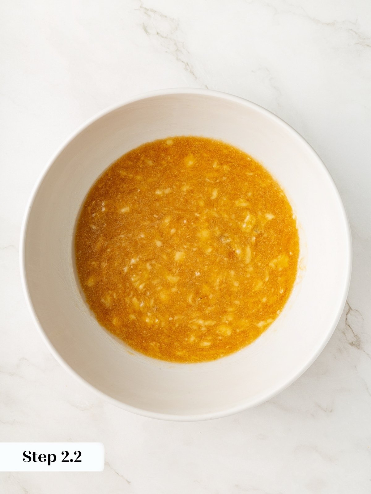 Coconut oil blending smoothly into the wet banana batter to form an even mixture.