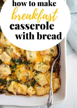 Baked breakfast casserole with golden cheese, sausage, and kale cubes nestled in rustic bread pieces.