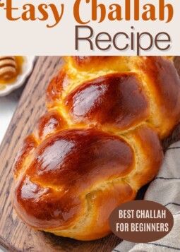 Warm homemade challah bread with soft crumb and detailed braid sitting on a wooden board.