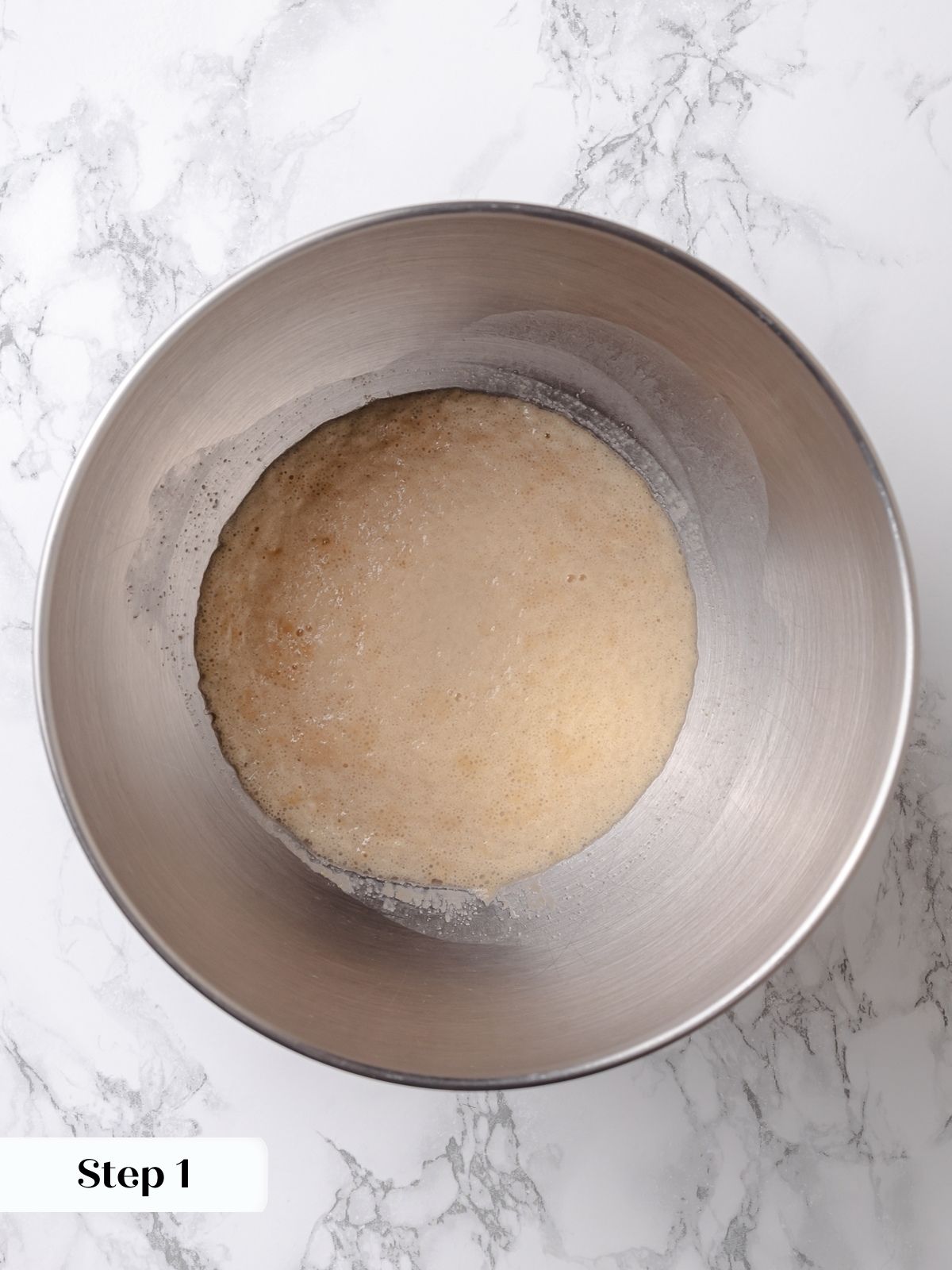 Yeast and honey mixture foaming in a bowl during the first step of challah preparation.