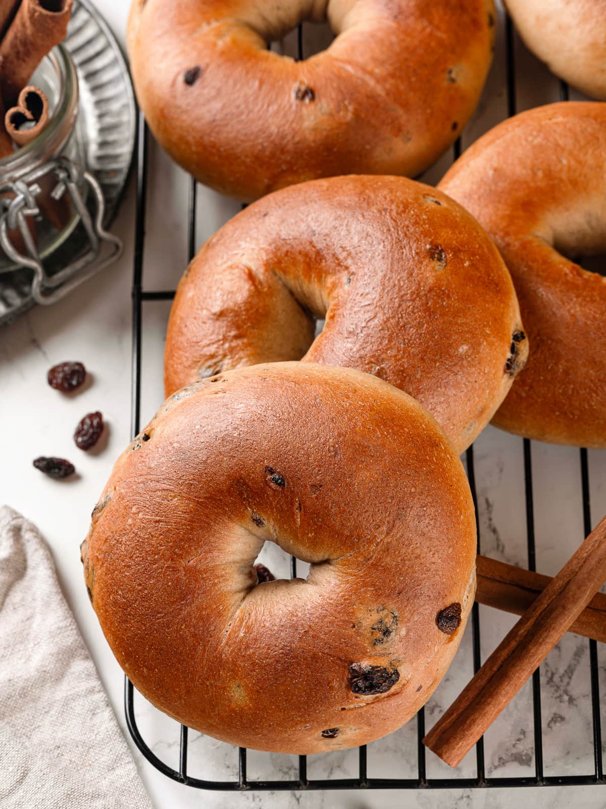 Fresh cinnamon raisin bagels cooling evenly on wire rack post-bake.
