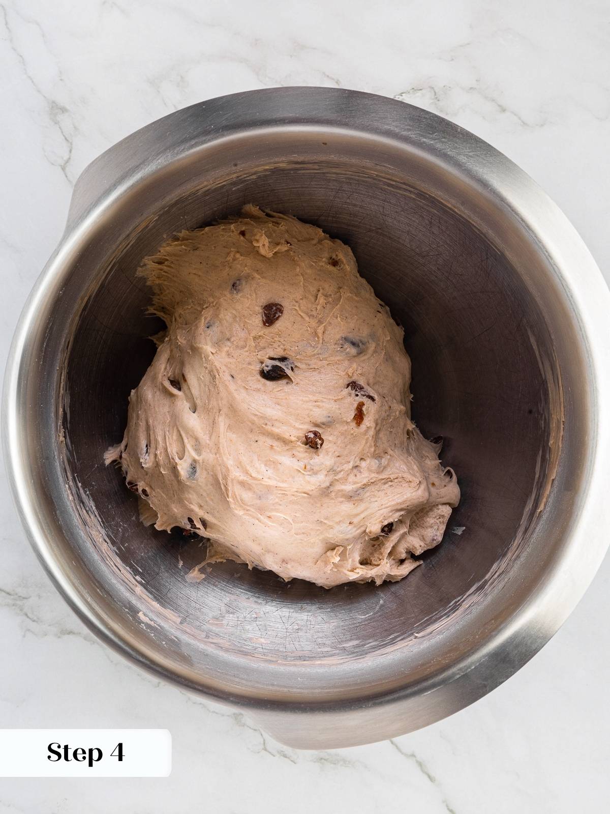 Raisins folded evenly into cinnamon dough, dark specks visible throughout.