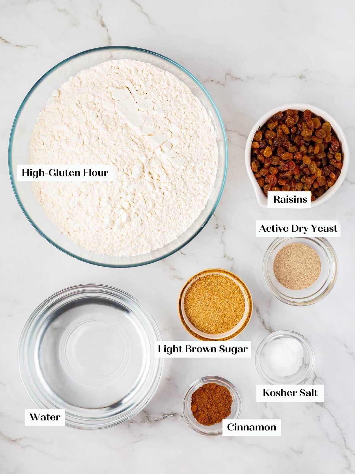 All ingredients laid out including flour, cinnamon, raisins, butter, and yeast.